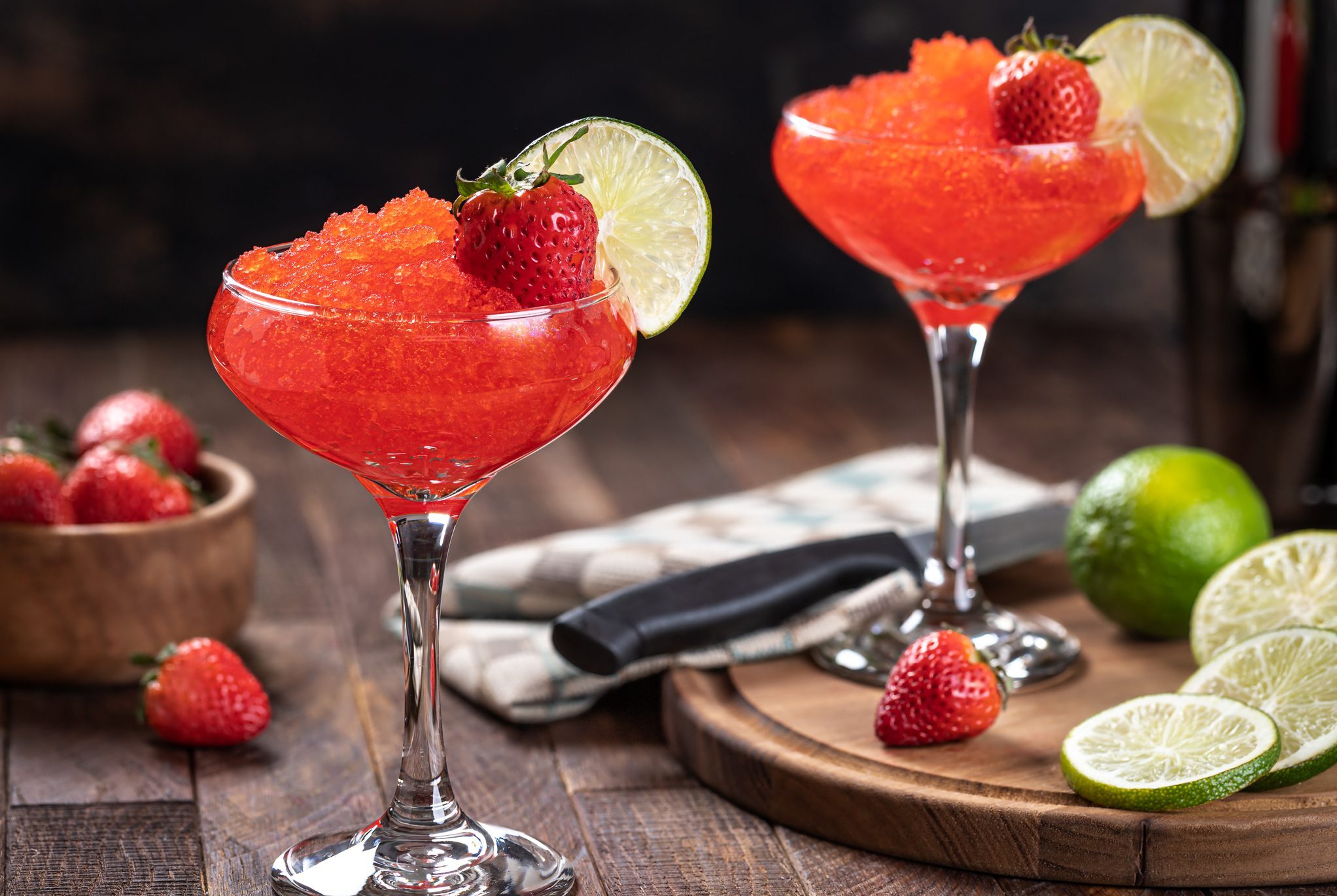 Two frozen strawberry margaritas with lime garnish
