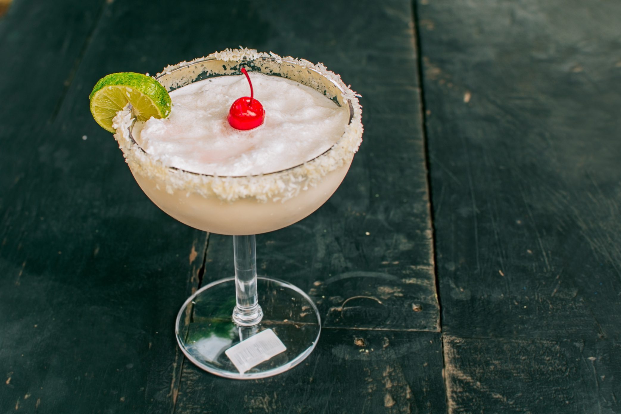 Frozen coconut cocktail with lime wedge and cherry