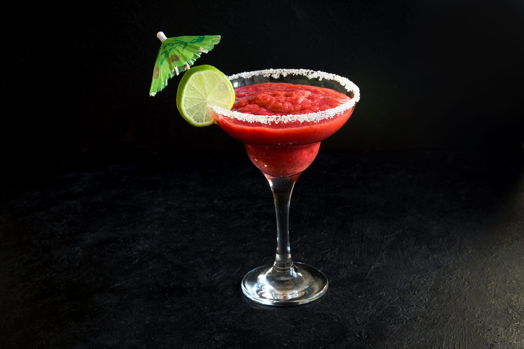 Frozen strawberry margarita with lime and umbrella